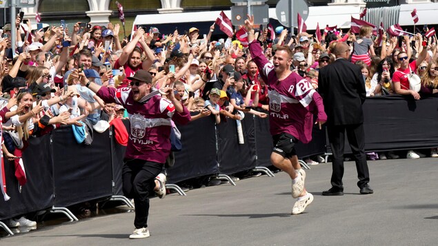 Les joueurs Rihards Bukarts et Oskars Cibulskis courent près d'une foule en liesse à Riga, en Lettonie. 