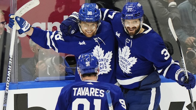 Trois joueurs de Toronto sourient et se sautent dans les bras.