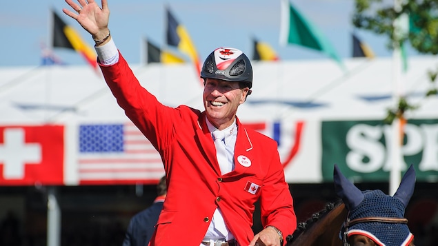Ian Millar salue la foule de la main sur son cheval