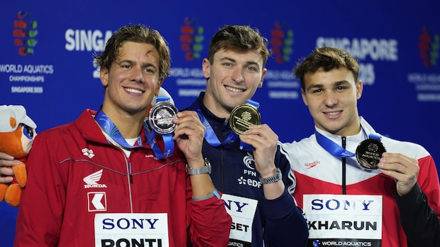 Trois nageurs montrent fièrement leurs médailles après la finale du 100 m papillon aux Mondiaux de sports aquatiques, à Singapour.