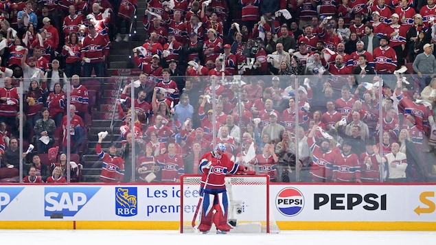 Des partisans debout manifestent leur satisfaction devant le gardien du Canadien, qui se tient debout devant son but pendant un arrêt de jeu.