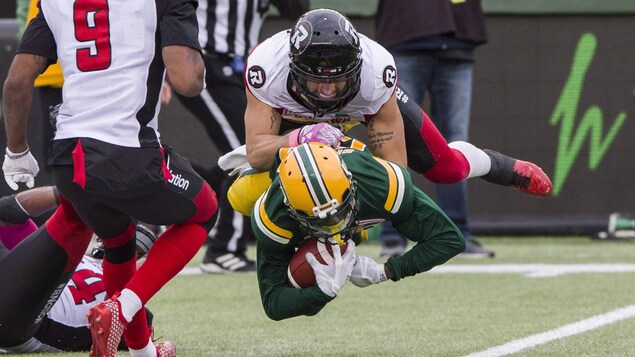 Un joueur vole dans les airs en plaquant un adversaire au football.