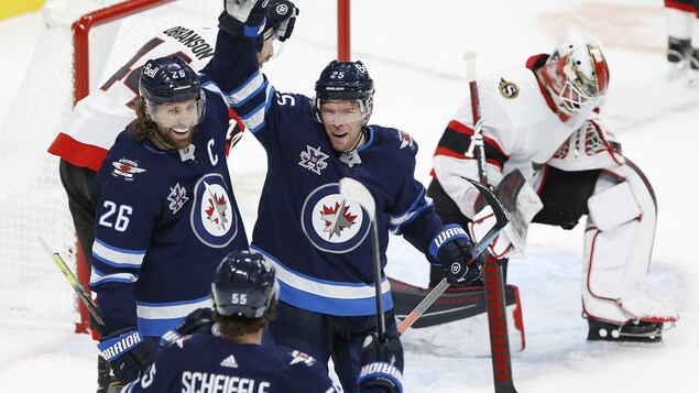 Trois joueurs de hockey se regardent en souriant.
