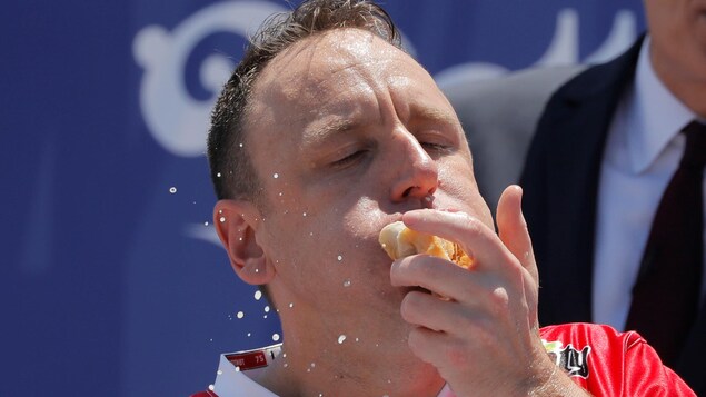 Un participant mange un hot dog pendant un concours