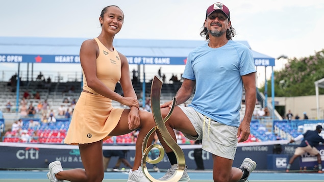 Une joueuse de tennis pose pour une photo avec son trophée aux côtés de son entraineur.