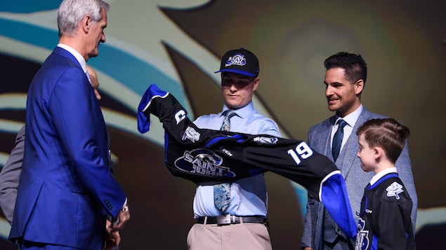 Un joueur de hockey enfile le chandail de sa nouvelle équipe