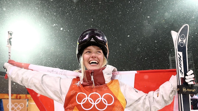 La skieuse acrobatique Justine Dufour-Lapointe sourit en brandissant le drapeau du Canada. La skieuse acrobatique Justine Dufour-Lapointe sourit en brandissant le drapeau du Canada.