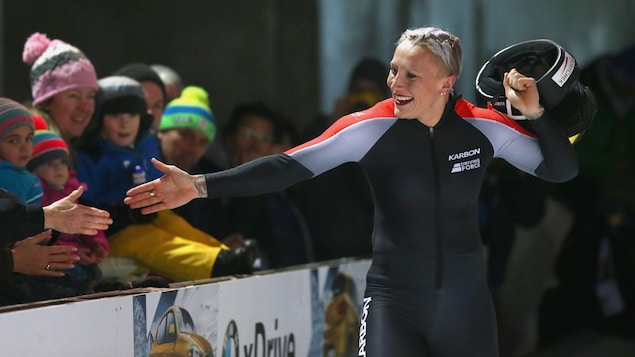 Kaillie Humphries enlève son casque en tendant la main à des spectateurs. Kaillie Humphries enlève son casque en tendant la main à des spectateurs.