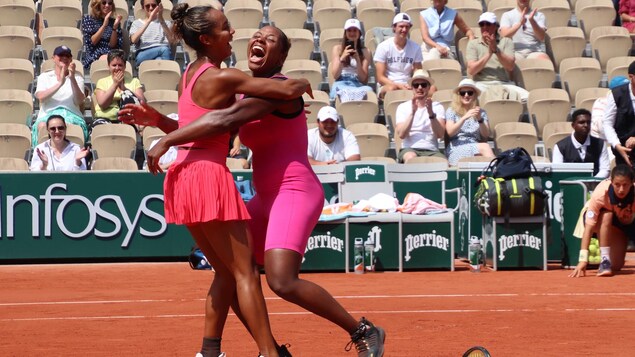 Deux joueuses de tennis se sautent dans les bras l'une de l'autre en souriant.