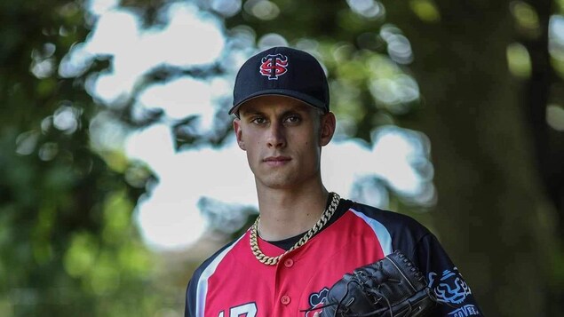 Le joueur de baseball tient son gant dans la main gauche.