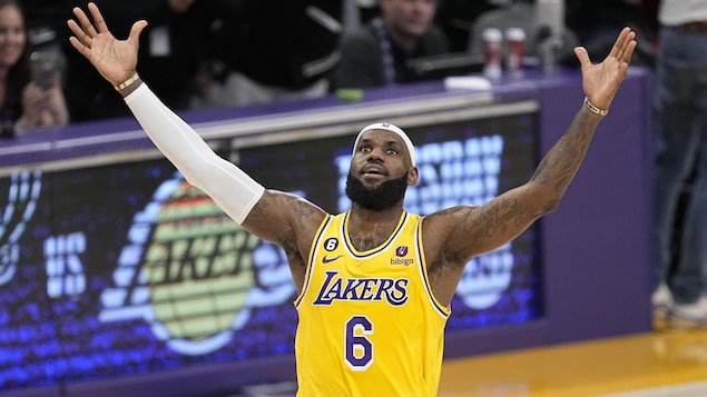 Un joueur de basketball lève les bras en l'air pour célébrer son nouveau record.