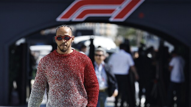 Un homme marche devant un panneau géant affichant le logo de la F1.