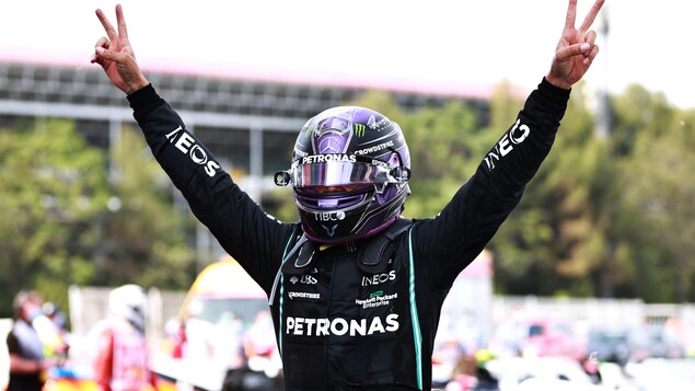 Hamilton célèbre en faisant des signes de paix des deux mains.