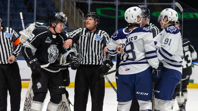 Des joueurs de l'Océanic sont tenus à l'écart sur la glace par des arbitres de la LHJMQ.