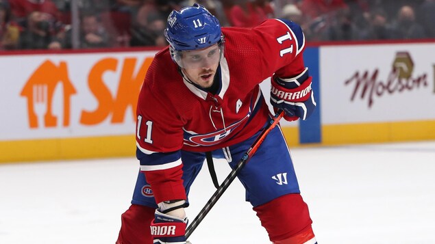Un joueur de hockey portant le chandail du Canadien de Montréal regarde la rondelle.