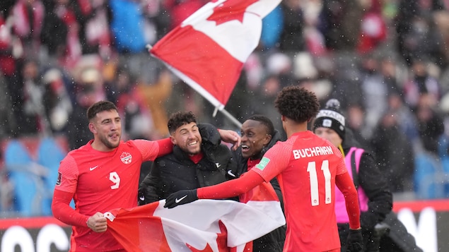 Lucas Cavallini, Jonathan Osorio, Richie Laryea et Tajon Buchanan célèbrent avec des drapeaux, sous la neige.