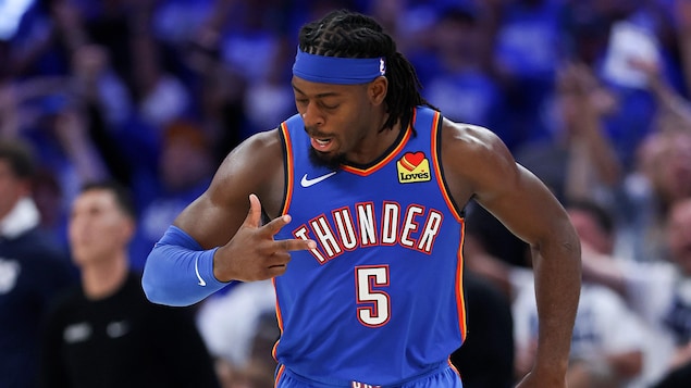 Il fait le chiffre trois avec sa main droite.