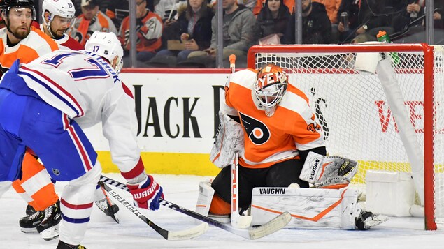 De dos, un joueur de hockey effectue un lancer vers un gardien.