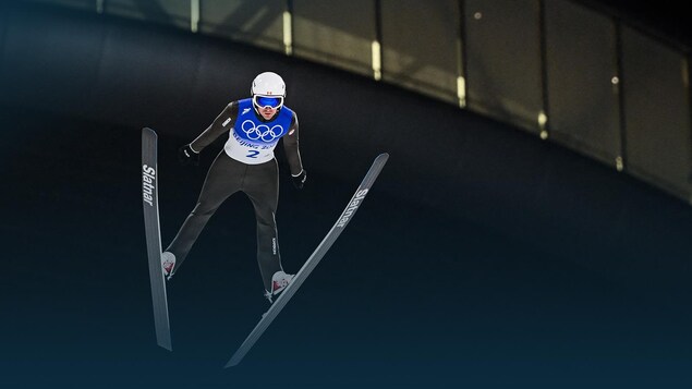 Un sauteur à ski semble suspendu dans els airs pendant un saut.