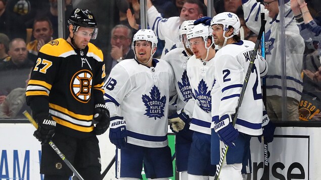 Les joueurs des Maple Leafs de Toronto célèbrent un but devant leur adversaire John Moore.