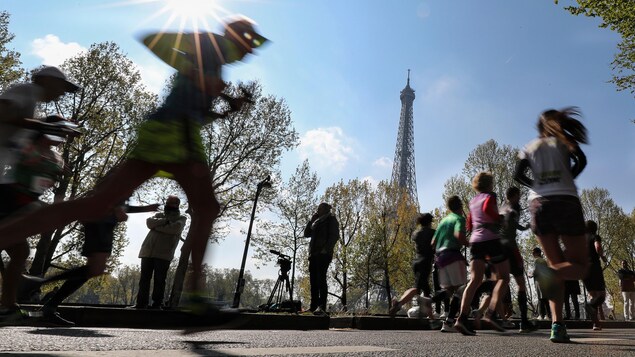 Les athlètes courent dans les rues de la capitale pendant le marathon de Paris, par beau temps.