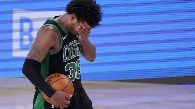 Le joueur des Celtics se porte la main au visage pour masquer son regard.