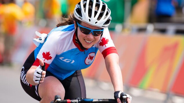 La paracycliste canadienne Marie-Claude Molnar, sur son vélo, le pouce levé, aux Jeux olympiques de Rio, en 2016. 