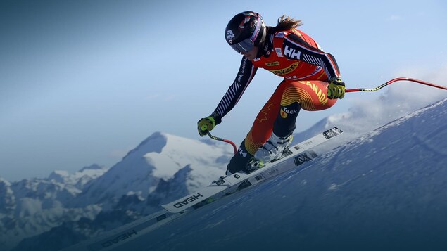 Une skieuse dévale une pente pendant une épreuve de ski alpin.