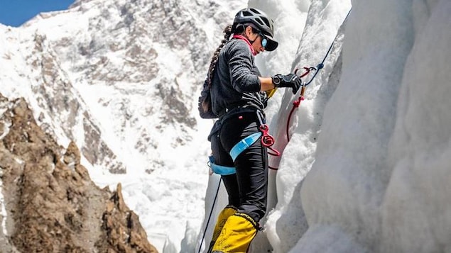 Une alpiniste grimpe une paroi de glace