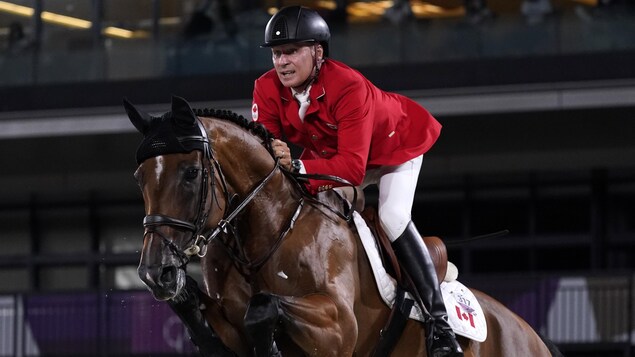 En selle sur son cheval, il franchit un obstacle.