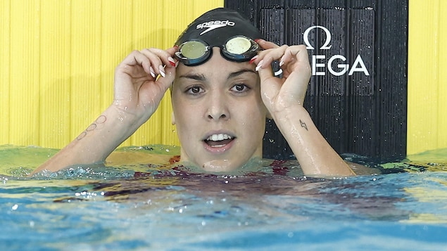 Une nageuse remonte ses lunettes après une course et regarde la caméra.