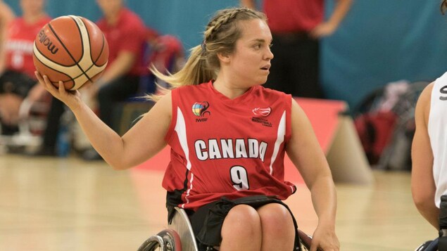 Elle tient un ballon de basket dans sa main droite.