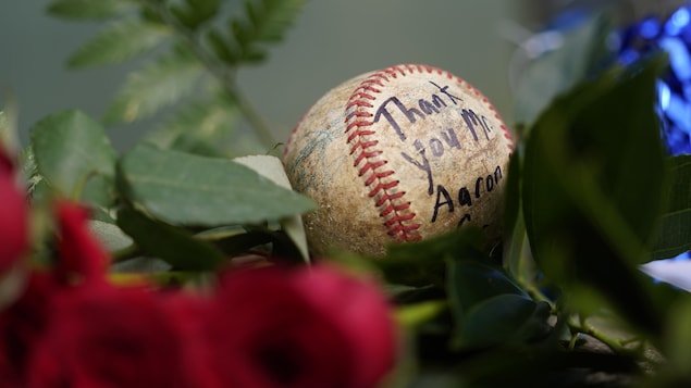 Balle de baseball déposée parmi des roses pour honorer Hank Aaron.