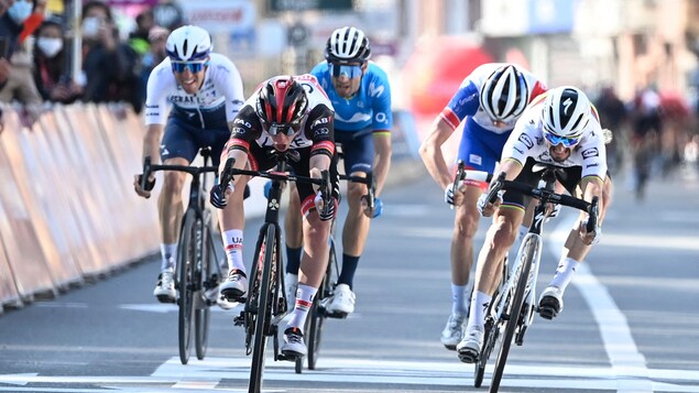 Cinq cyclistes franchissent le fil d'arrivée d'une course sur route.