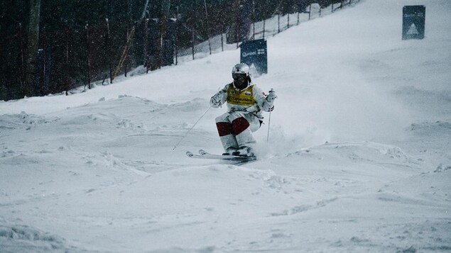 Un skieur descends une piste de bosses.
