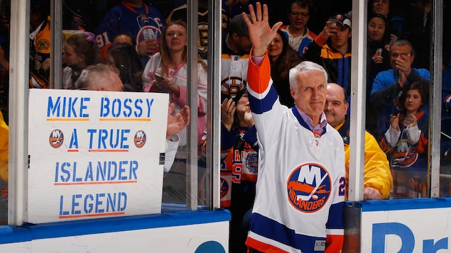 Un homme vêtu d'un chandail de hockey salue la foule dans un amphithéâtre.