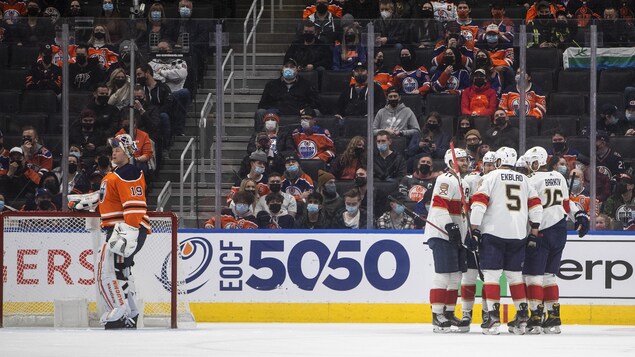 Des partisans déçus regardent les joueurs des Panthers célébrer un but à côté du gardien des Oilers.