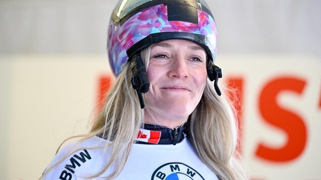 Le casque relevé, la femme affiche un sourire timide. 