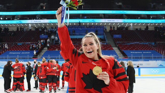 Elle soulève un bouquet de fleurs sur la glace après un triomphe olympique.