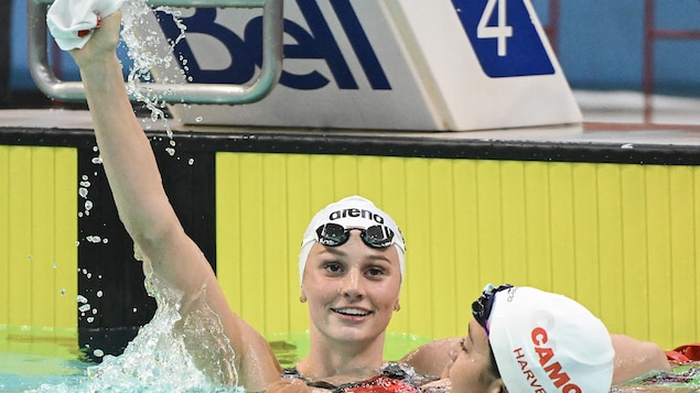 Summer McIntosh lève la main et sourit après sa course dans la piscine.