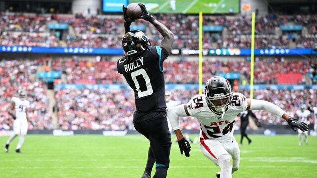 Calvin Ridley attrape le ballon dans la zone des buts à côté d'un joueur défensif des Falcons en déséquilibre.