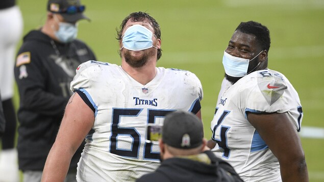 Deux joueurs de football portent un masque de protection, dont un qui l'a mis sur ses yeux, plutôt que sur sa bouche.