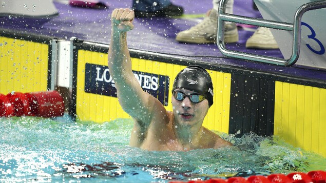 Un nageur lève le poing au ciel pour célébrer sa victoire.