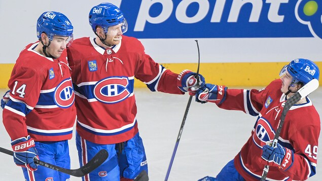 Trois hockeyeurs du Canadien de Montréal célèbrent un but.