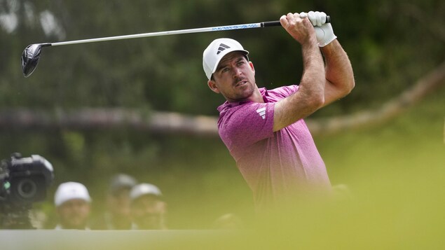 Un golfeur termine son élan et regarde la balle. 
