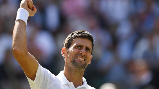 Le Serbe Novak Djokovic sourit et lève le point en l'air. Le Serbe Novak Djokovic sourit et lève le point en l'air.