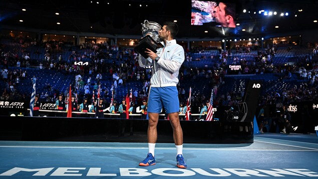 Le joueur de tennis Novak Djokovic embrasse un trophée.
