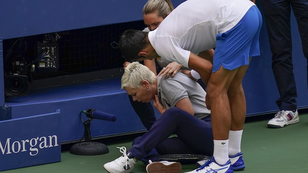 Djokovic est penché près de la juge qu'il a involontairement frappée avec une balle.