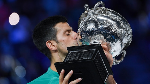 Un joueur de tennis embrasse le trophée qu'il vient de remporter aux Internationaux d'Australie.