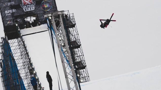 Olivia Asselin dans les airs après un saut, les skis croisés.